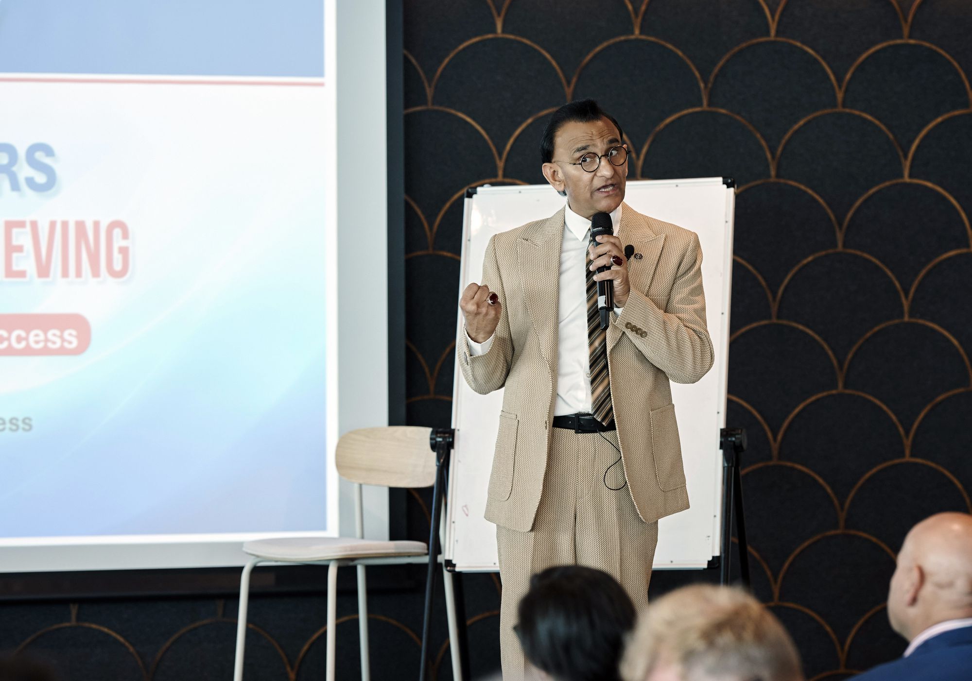 Zaffar Khan speaking into a microphone beside a whiteboard