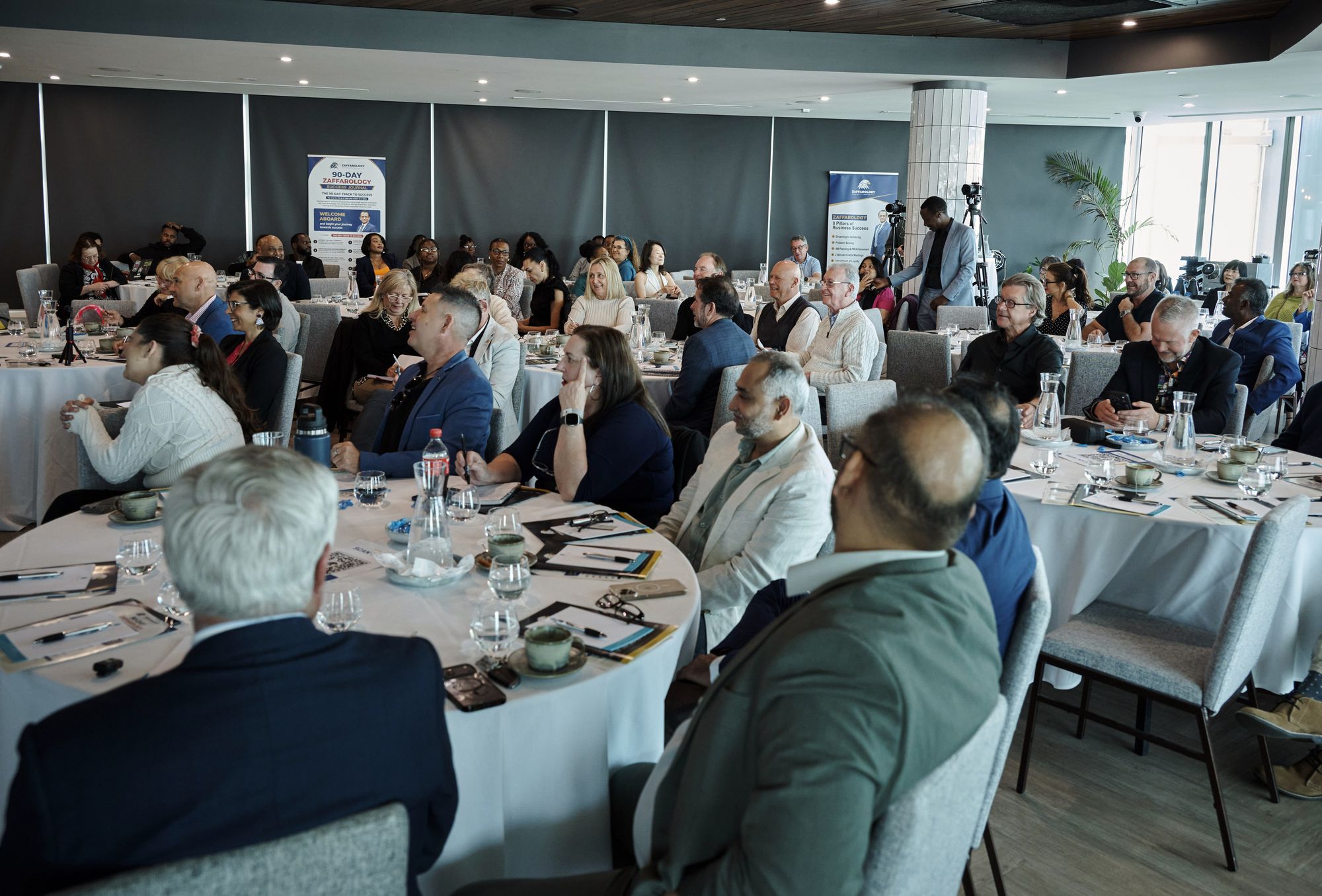 Attendees smiling and applauding at their tables