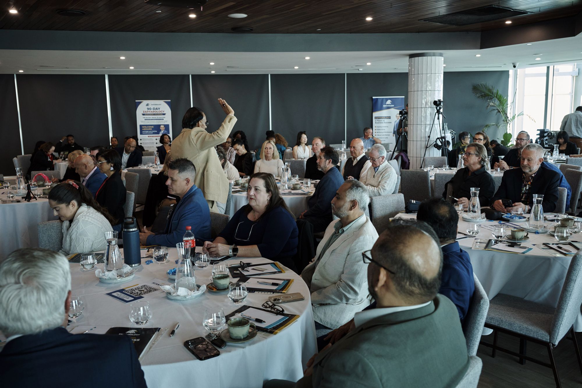 An attendee standing with her hand raised to ask a question from the floor