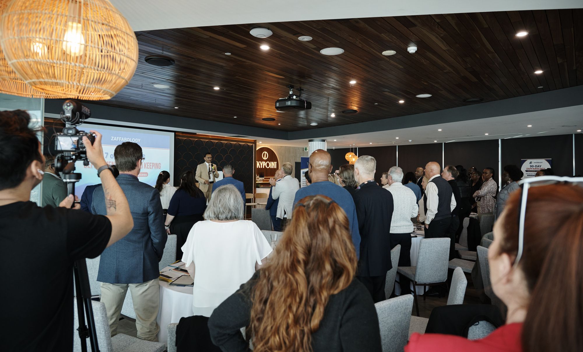 A videographer filming the room while attendees stand and mingle