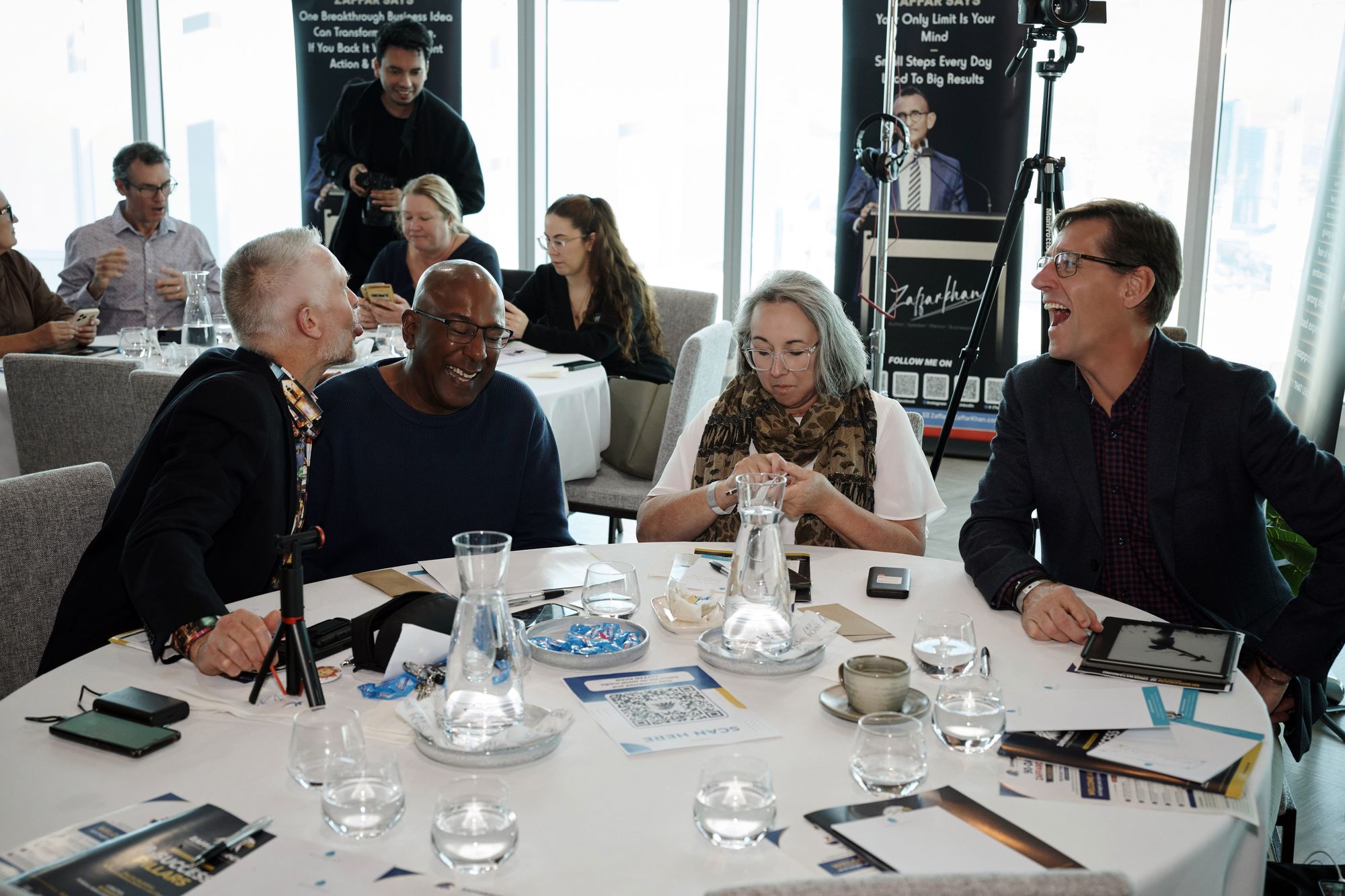 Four attendees laughing together around their table